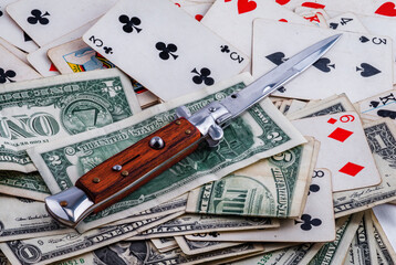 Automatic knife on background of money and playing cards
