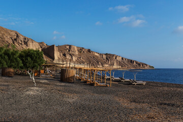 Santorini - village Thira, beautiful bay surrounded by high rocks, Exo Gialos beach with umbrellas...