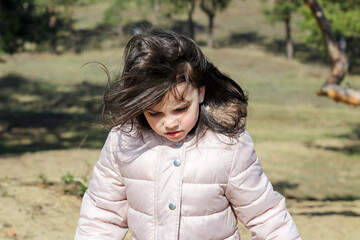 Closeup portrait of angry white girl with long hair rising uphill on blurred natural background