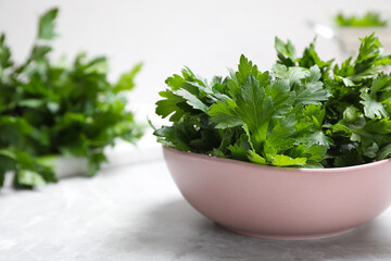 Fototapeta premium Fresh green parsley in bowl on white table, space for text
