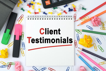 On the table is a calculator, diary, markers, pencils and a notebook with the inscription - Client Testimonials