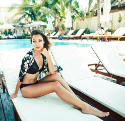 young pretty woman at swimming pool relaxing in chair, fashion look in lingerie at hotel, lifestyle...