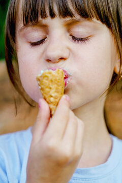 Close up beautiful child girl eating ice cream in waffles cone. Vertical image.