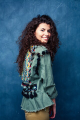 young pretty woman with curly brunette hair posing cheerful on blue background, lifestyle people concept