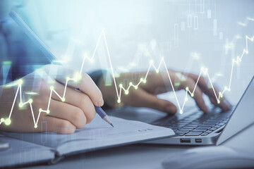 Double exposure of businesswoman hands typing on computer and forex graph hologram drawing....