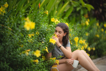 Young cute woman smelling yellow flowers, relaxing in the garden