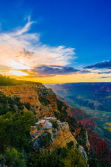 Naklejka na ściany i meble Panoramic image of the colorful Sunset on the Grand Canyon in Grand Canyon National Park from the south rim part,Arizona,USA, on a sunny cloudy day with blue or gloden sky