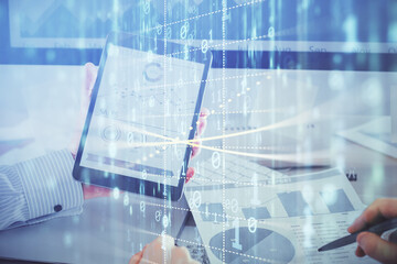 Double exposure of man's hand holding and using a digital device and data theme hologram drawing. Technology concept.