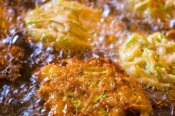 Fried vegetable fritters with zucchini, carrots, herbs, eggs, and cheese in boiling oil.