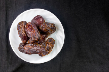 Big luxury dried date fruit in bowls on the dark surface, kurma ramadan kareem concept, close up.