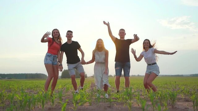 Five happy friends jumping holding hands at sunset. Slow motion video. Slow motion video.