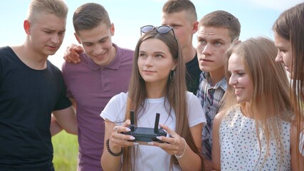 Cheerful friends control the drone using the remote control.