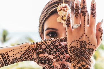 Beautiful Sikh model posing with intricate henna designs beneath bright clear skies