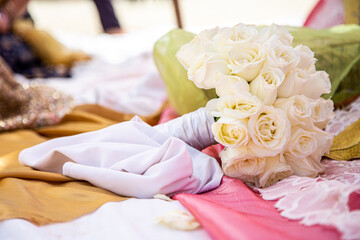 White rose bouquet resting on linens beneath brightly lit skies