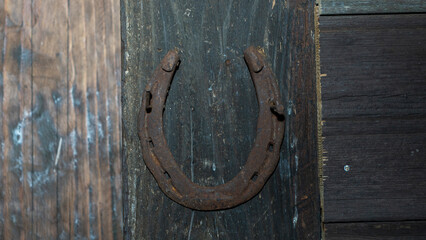 Horseshoe on a brown door background. Horseshoe for good luck. Old wooden door. Space for text. Texture concept.