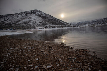 lake in the snowy mountains with rocky shore