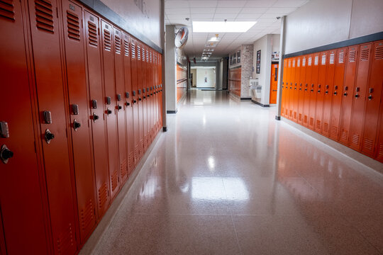 Empty hallway in school lined with orange lockers