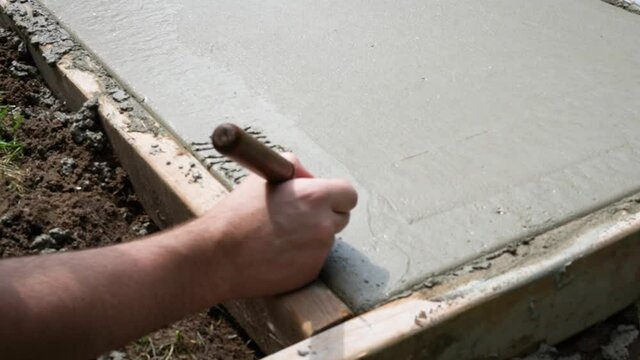A newly married couple carves their initials into newly poured concrete.