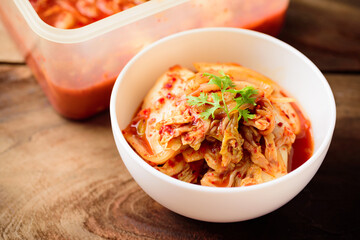 Kimchi cabbage in a bowl and food box on wooden table, Korean food