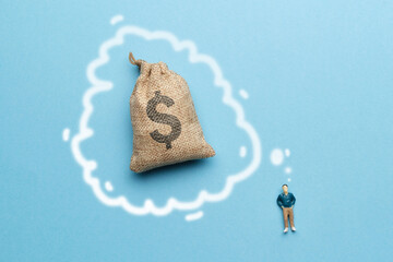 The concept of the dream of wealth. The figurine of a man next to a bag of money.