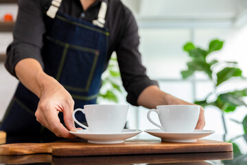 Barista pouring black coffee to white cup for service in coffee shop.