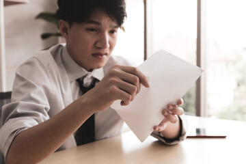 young business man at his desk stunned by something he is reading on some paper sheets from envelope