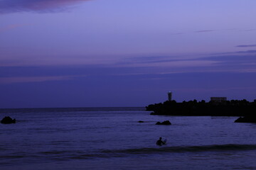日没後の海に残るサーファー