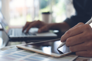 home interior designer or decorator using stylus pen on digital tablet and working on laptop computer in office