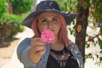pink haired woman showing a pink flower