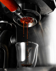Espresso dripping from a machine into a clear shot glass