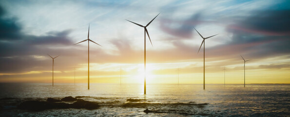 wind turbines spinning at sunset over the sea