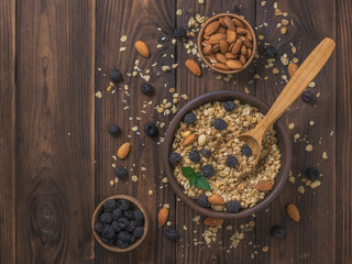 Granola with black raspberries and almonds on a wooden table.