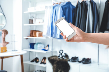 Woman with mobile phone in modern clothes store