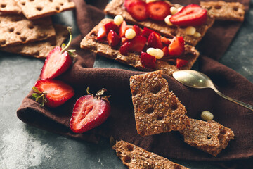 Tasty crispbreads with chocolate and strawberry on dark background
