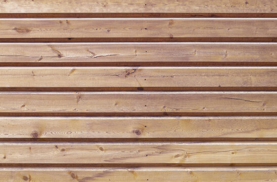 A close-up of a fragment of a wall made of horizontal strug wooden planks. Horizontal orientation, front view. Selective focus. Wooden texture, background.