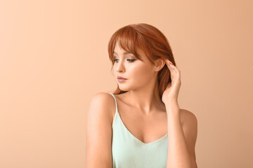 Beautiful young redhead woman on color background