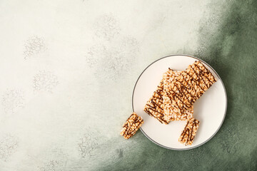Plate with crispy rice bars on color background
