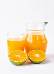 Jug, glass of orange juice and orange fruits with green leaves  on white background
