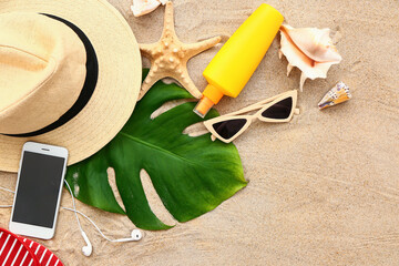 Beach accessories and mobile phone on sand background