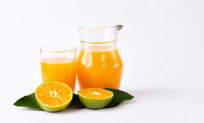 Jug, glass of orange juice and orange fruits with green leaves  on white background