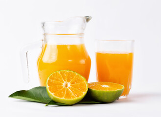 Jug, glass of orange juice and orange fruits with green leaves  on white background