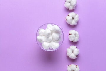 Cotton balls with flowers on color background