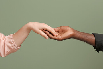Caucasian woman and African-American man holding hands together on color background. Racism concept