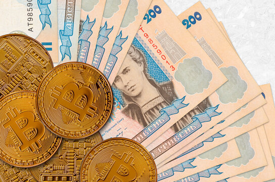 200 Ukrainian hryvnias bills and golden bitcoins. Cryptocurrency investment concept. Crypto mining or trading