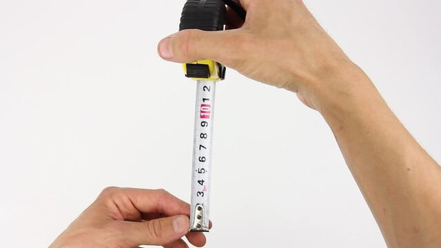 human hands pull the measuring tape out of tape measure and measure the dimensions, length width height and diagonal, close up view on white background