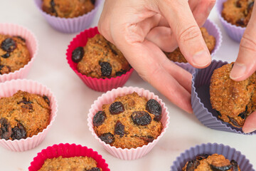 Bran muffins with dry cranberries close up in baking silicon cups on white background. Healthy food, good source of dietary fiber