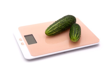 Green cucumbers on kitchen scales on a white background. The concept of weighing.