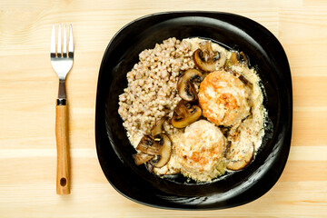 Chicken meatballs with mushrooms in a creamy sauce with a side dish of green buckwheat.