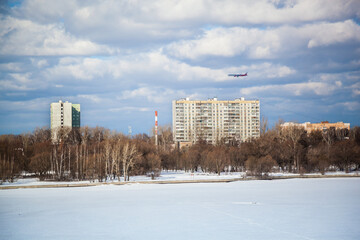 The plane when landing over the city. You can see old houses, trees, covered with ice and snow.