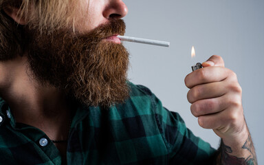 Fototapeta premium lightng the cigarette. bearded man. smoking cigarette habit. brutal hipster with moustache. fashion model in casual clothes. male beauty standard. looking so trendy. Confident and handsome brutal man